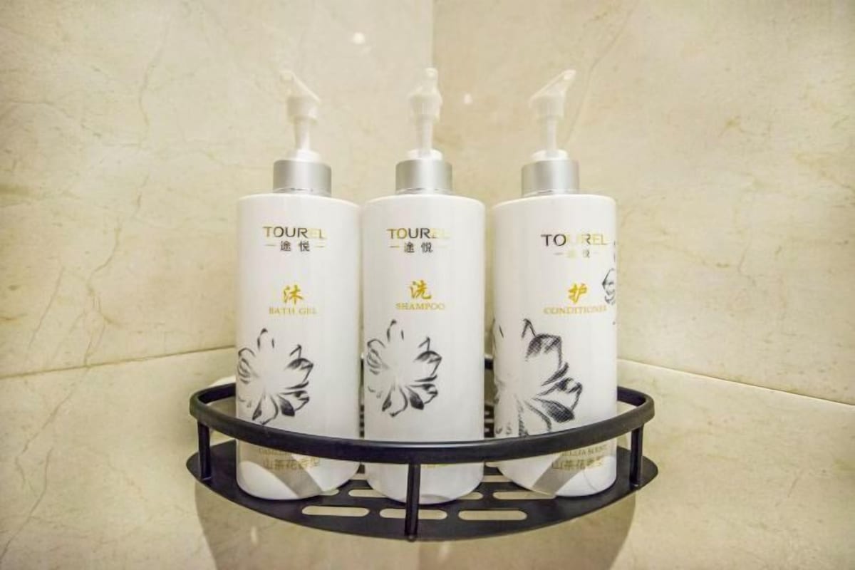 Three bottles of TOUR L bath gel, shampoo, and conditioner in a black tray.