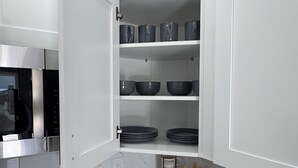 Una cocina moderna con armarios blancos, microondas integrado y una estación de café.