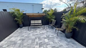 Un patio con pérgola, asientos y plantas en macetas.