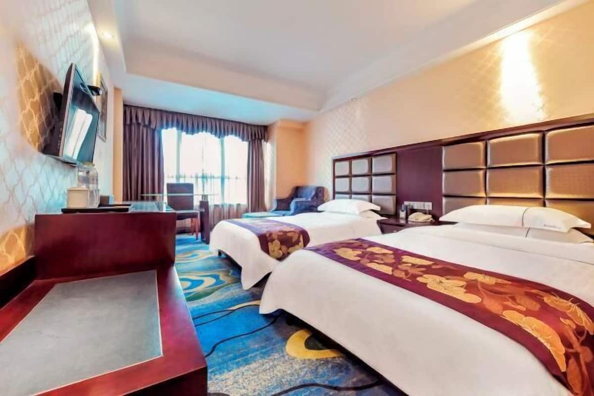 A hotel room with two beds, a desk, a chair, a TV, and a large window with curtains.