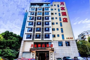 Un hotel de varios pisos con un letrero vertical llamativo y una entrada a nivel de calle.