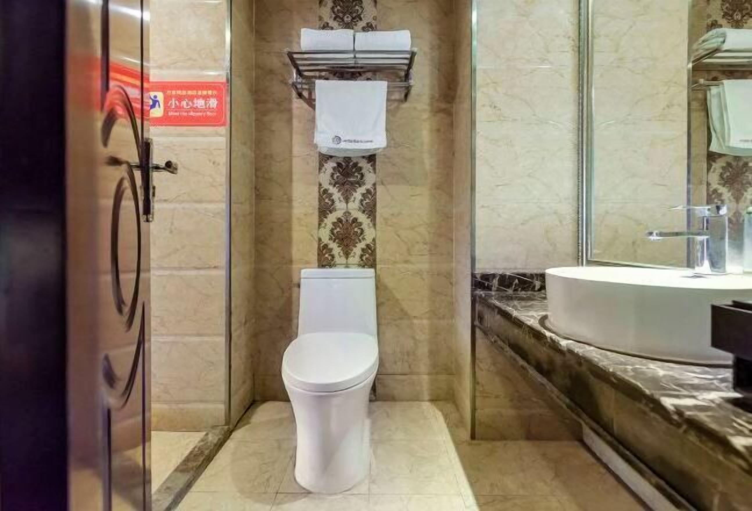 A bathroom with a toilet, a towel rack, and a sink with a mirror.