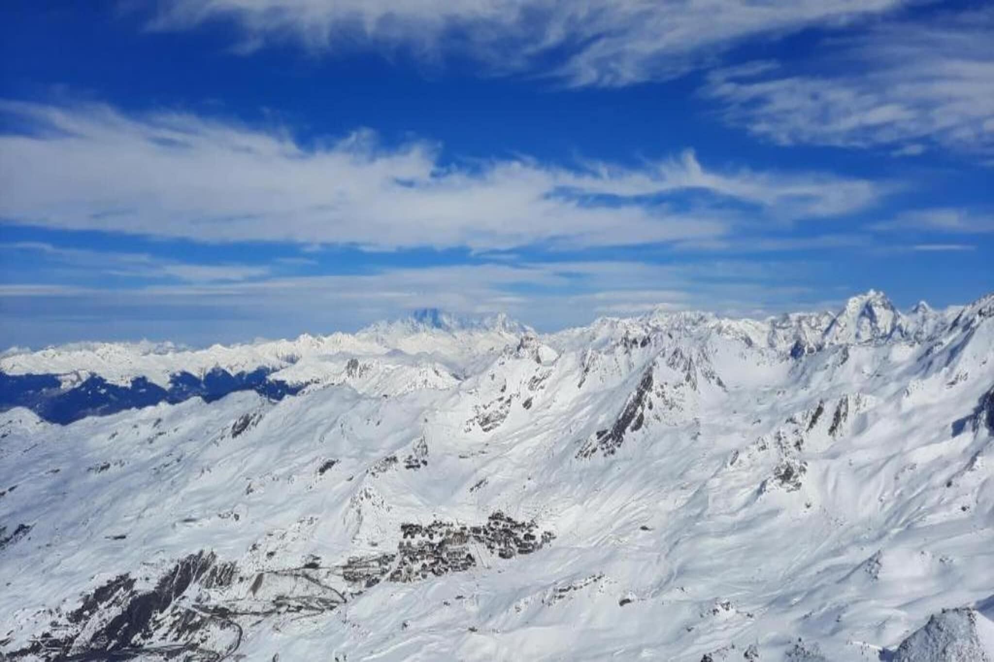 Ein verschneites Gebirge unter blauem Himmel.