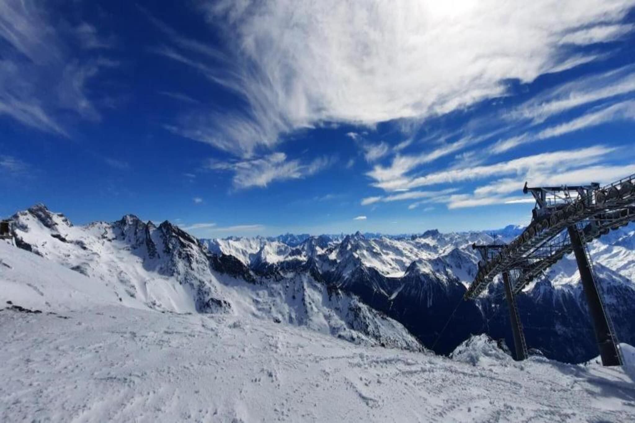A snowy mountain landscape with a clear sky and a ski lift structure.