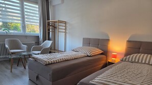 Ett sovrum med två sängar, en stol, ett bord och ett element.