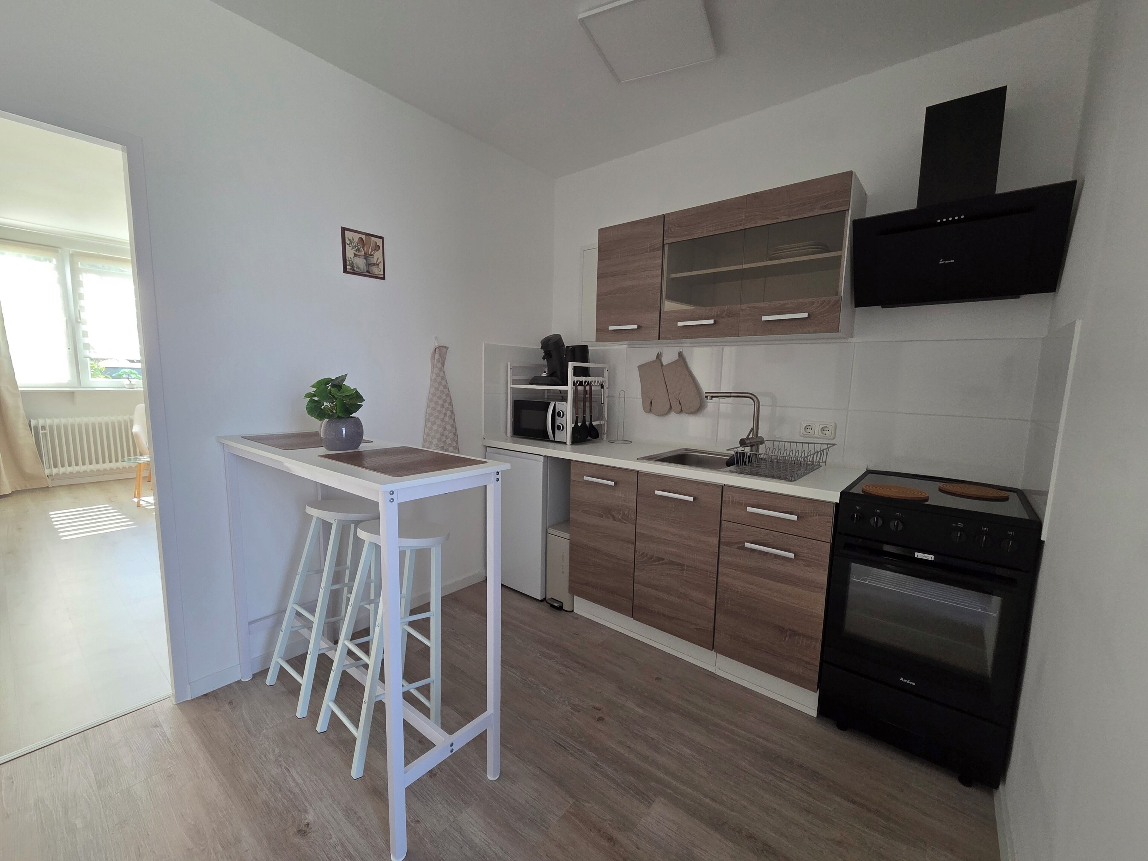 Eine moderne Küche mit Essbereich, Holzschränken, einer Mikrowelle, einem Backofen und einem kleinen Topfpflanzen.