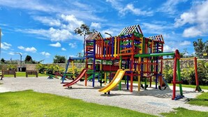 Un parque infantil con una estructura para escalar, toboganes y columpios.