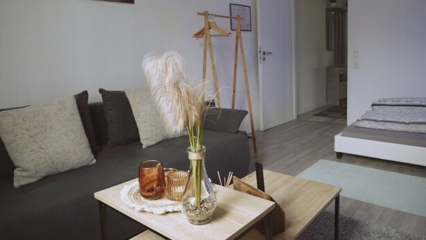 Un salon moderne avec un canapé, une table basse et un vase contenant des plantes séchées.