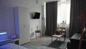 Une chambre moderne avec un lit, un bureau, une chaise, un téléviseur et une fenêtre avec des rideaux.