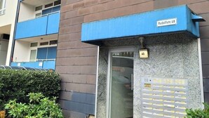 Un bâtiment moderne avec un auvent bleu et une enseigne indiquant « Rudolfstr. 48 ».