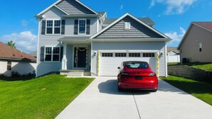 A two-story house with a garage, a red car parked in front, and a well-maintained lawn.
