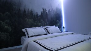 A bedroom with a large bed, a nightstand, and a wall mural of a forest.