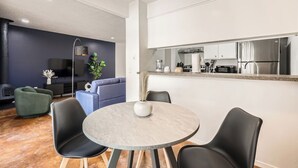 A modern living room with a round table, two black chairs, a blue sofa, a green armchair, a flat-screen TV, and a fireplace. - Comfy King Suite Getaway | Sleeps 4 | Pool, Prkg (Austin)