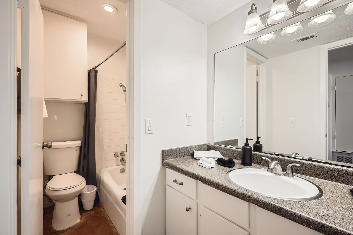A modern bathroom with a toilet, bathtub, and a sink with a large mirror.