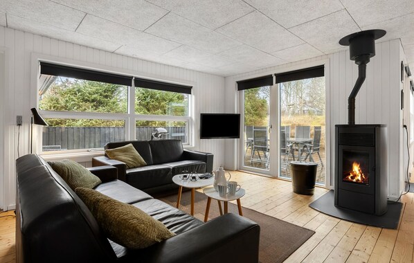 A modern living room with a black leather sofa, a flat-screen TV, and a wood-burning stove. - Awesome home in Hals with WiFi (Hals)