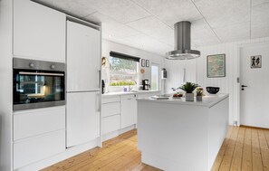 A modern kitchen with white cabinetry, a built-in oven, a stainless steel range hood, and a wooden floor. - Awesome home in Hals with WiFi (Hals)