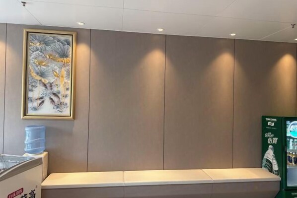Una habitación con un banco, dispensador de agua y una obra de arte enmarcada en la pared.