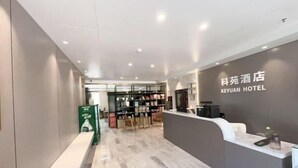 A modern hotel reception area with a marble floor, a reception desk, and a display of amenities. - Keyuan hotel (Beijing)