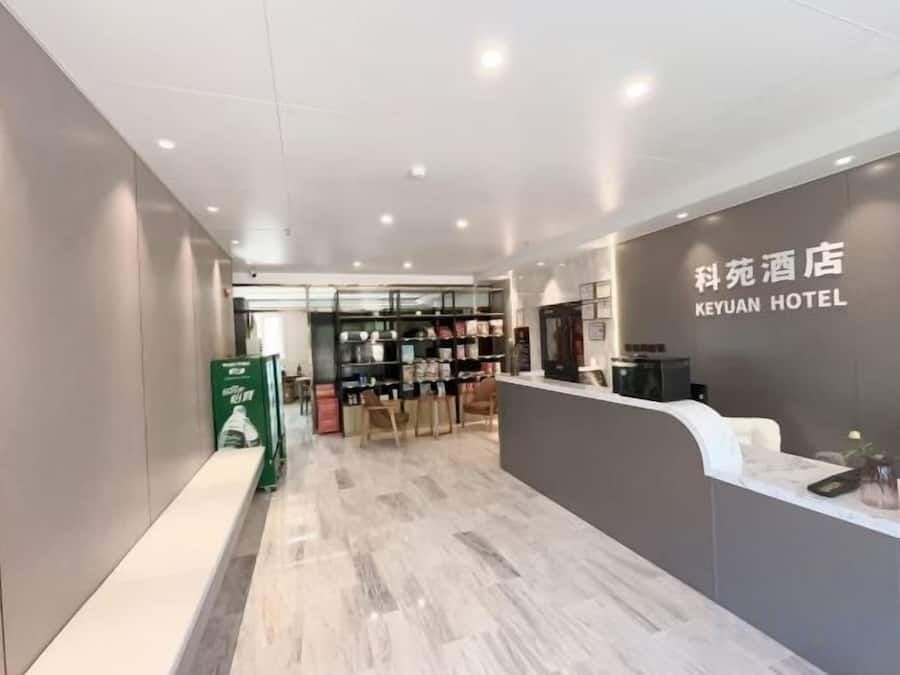 A hotel reception area with a reception desk, a seating area, and a view into the hotel's interior.