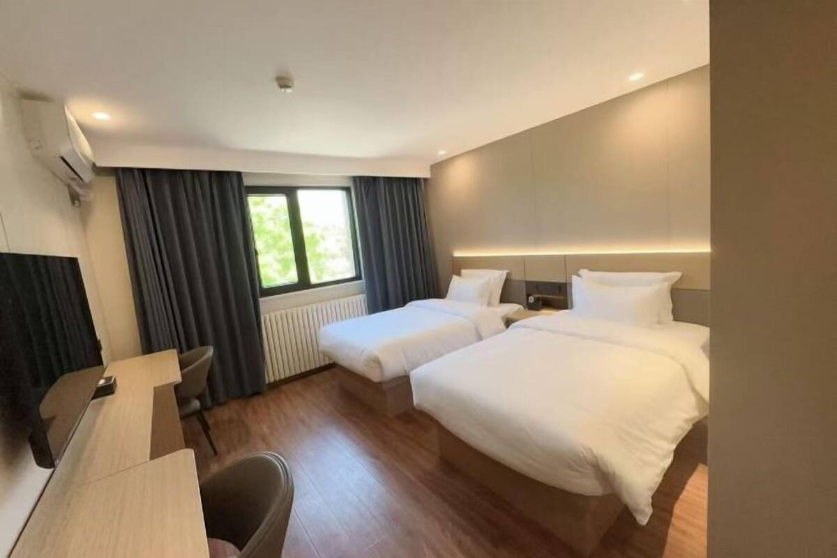 A hotel room with two beds, a desk, and a chair.