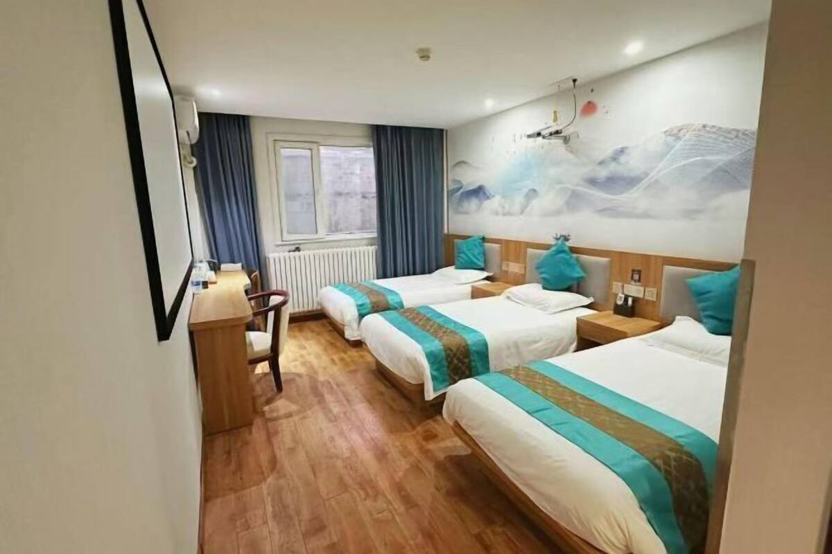 A hotel room with two beds, a desk, a chair, and a window with curtains.