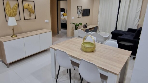 Een moderne eethoek met een houten tafel, witte stoelen en een hangende hanglamp.
