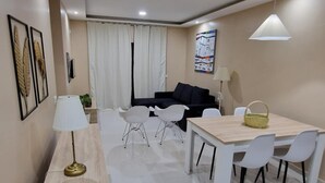 Een moderne woonkamer met een bank, een eettafel met stoelen en een salontafel.