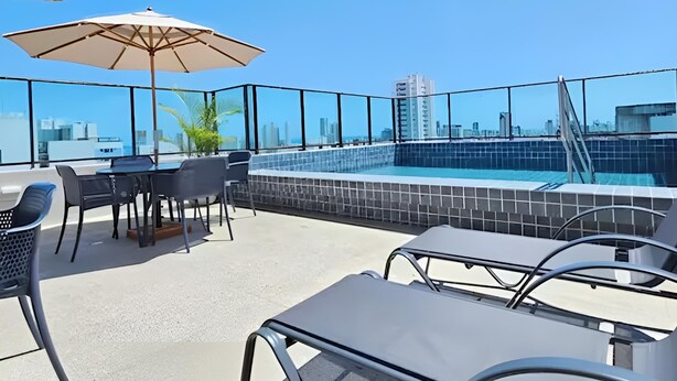 A rooftop terrace with a pool, outdoor seating, and a city skyline view. - Flat in Boa Viagem (2 km from the airport) (Boa Viagem Recife)