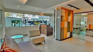 A modern living room with a sofa, a small table, and a glass partition. - Flat in Boa Viagem (2 km from the airport) (Boa Viagem Recife)