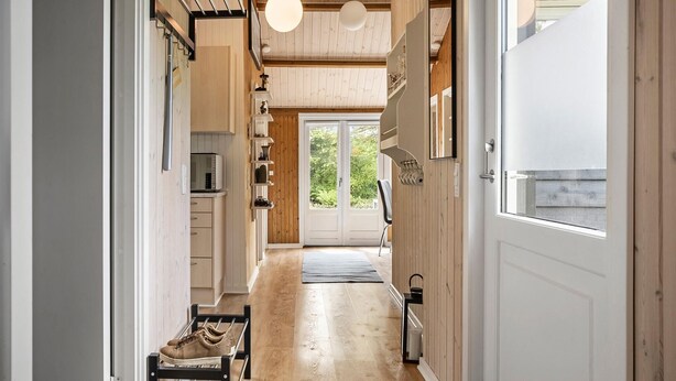 A narrow hallway with wooden walls and a wooden floor, leading to a door with a glass panel. - Amazing home in Tarm with WiFi (Tarm)