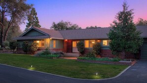 A two-story house with a front porch, a garage, and a well-maintained lawn. - Fireplace, Soaking Tub & Peaceful Surroundings (Mariposa)