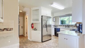 A modern kitchen with white cabinetry, a stainless steel refrigerator, and a window providing natural light. - Fireplace, Soaking Tub & Peaceful Surroundings (Mariposa)
