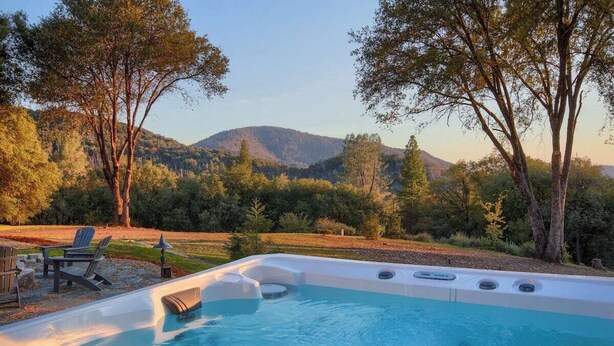 A hot tub in a natural setting with trees and a mountain in the background. - Fireplace, Soaking Tub & Peaceful Surroundings (Mariposa)