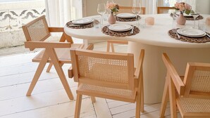 A dining area with a round table set for four, surrounded by wicker chairs.