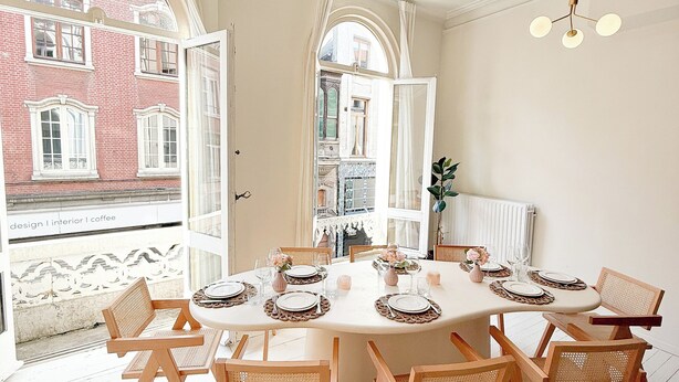 A dining area with a round table set for six, surrounded by wicker chairs.