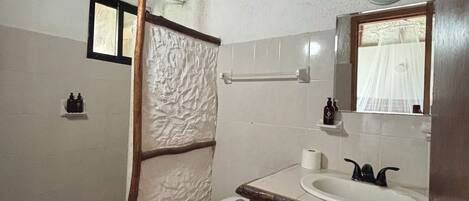 Une salle de bain avec un plafond en bois, des toilettes blanches, un lavabo avec un miroir et une serviette accrochée au mur.