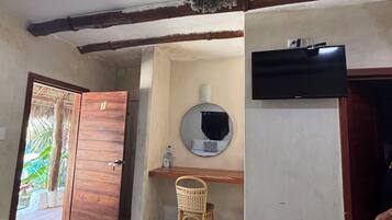 Una habitación con dos camas, un escritorio de madera, una silla, un espejo y un televisor.