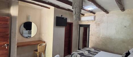 Une chambre avec deux lits, un bureau, une chaise, un miroir et un luminaire suspendu.