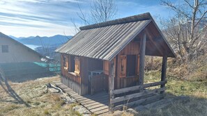Een rustieke houten hut met een schuin dak, een houten veranda en een klein raam.