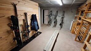 Een skiopslag met houten wanden, ski's en een bank.