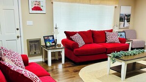 Un salon avec deux canapés rouges, une table basse et une petite table d’appoint.