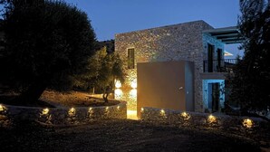 A stone building with a balcony, surrounded by trees and a stone wall.