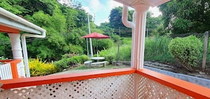 A garden with a red umbrella, a stone bench, and a white fence. - Mandarin Vacation Villa 3 Bedrooms - Toco (Cumana)