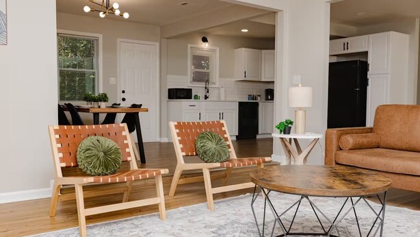 A modern living room with two wooden chairs, a round coffee table, and a brown sofa.