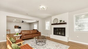 A spacious living room with a brown leather sofa, a round coffee table, and a fireplace.
