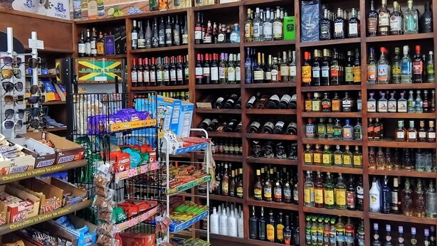 Ein Getränkeladen mit Regalen voller verschiedener Alkoholflaschen und einer Auslage mit Pralinen.