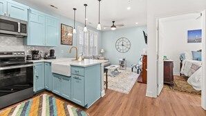 A modern kitchen with light blue cabinets, stainless steel appliances, and pendant lighting.