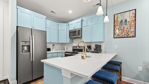 A modern kitchen with light blue cabinets, stainless steel appliances, and a central island with bar stools.