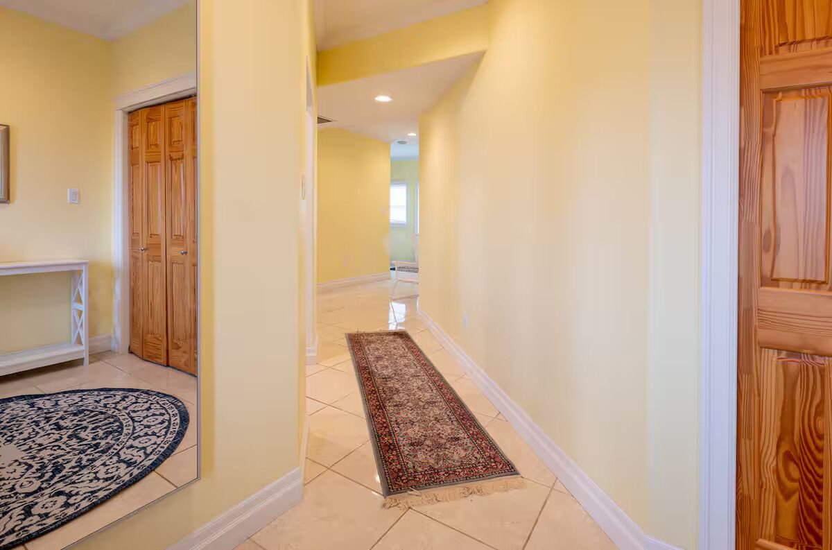 A hallway with a wooden door, a bench, and a patterned rug.
