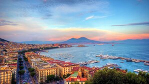 A coastal cityscape with a marina, buildings, and a mountain in the background. - Room to dream (San Valentino Torio)